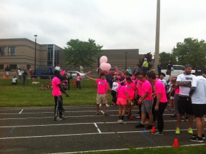 Runners from John Paul Secondary School at the start of the track with pink shirts and balloons