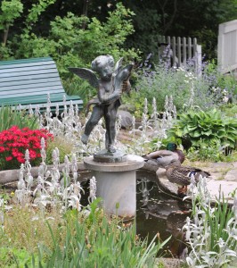 A cherub statue holding a dolphin on a pedestal in a pond