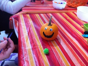 A tiny pumpkin with googly eyes and a smile painted on