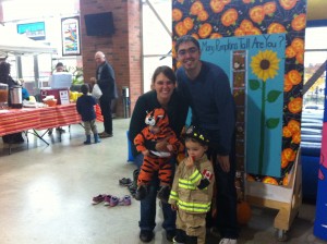 A woman and a man with a young boy dressed as a firefighter, and a baby dressed as a tiger